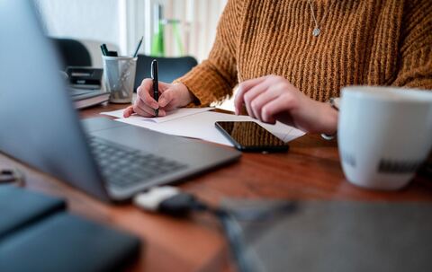 Frau sitzt mit einem Laptop am Tisch