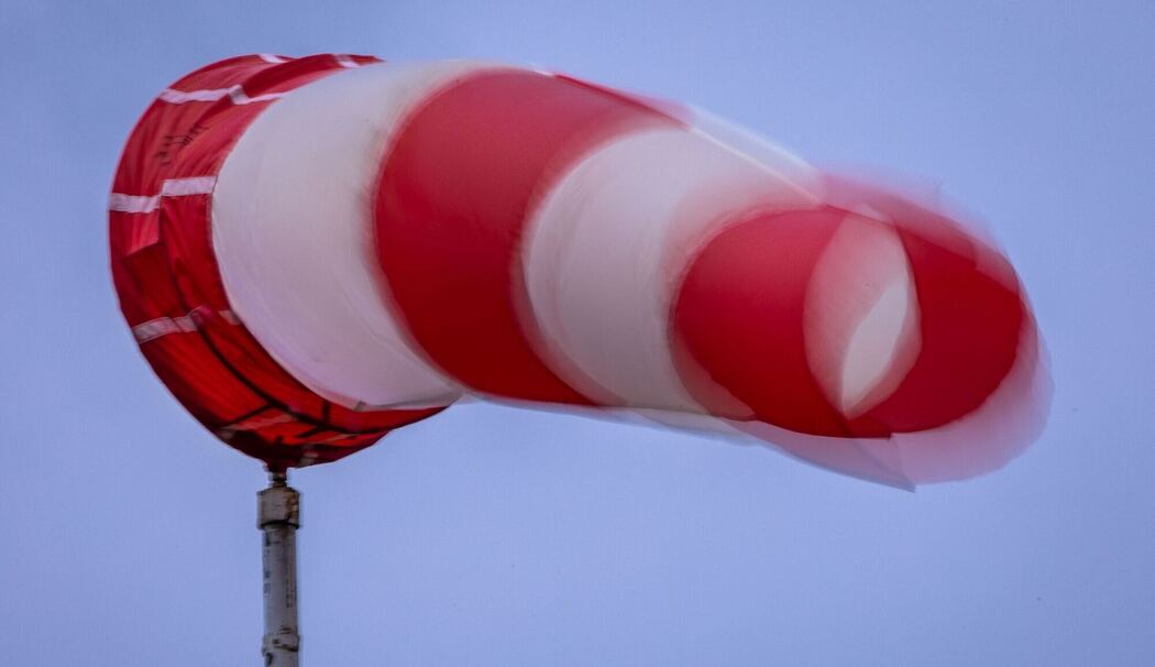 Windsack weht bei Regen und kräftigem Wind am Mast Windsack weht bei Regen und kräftigem Wind am Mast
