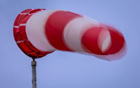 Windsack weht bei Regen und kräftigem Wind am Mast