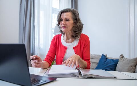 Eine ältere Frau arbeitet am Laptop.