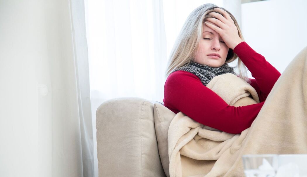 Eine Frau sitzt krank auf einem Sofa Eine Frau sitzt krank auf einem Sofa