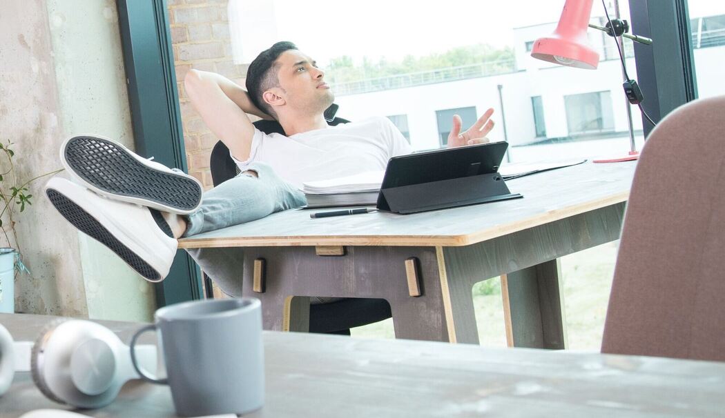Mann schaut an seinem Schreibtisch aus dem Fenster Mann schaut an seinem Schreibtisch aus dem Fenster