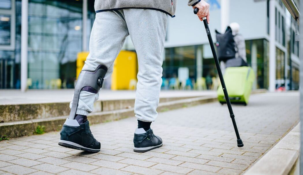 Ein Mann läuft mit einer Gehhilfe auf der Straße Ein Mann läuft mit einer Gehhilfe auf der Straße