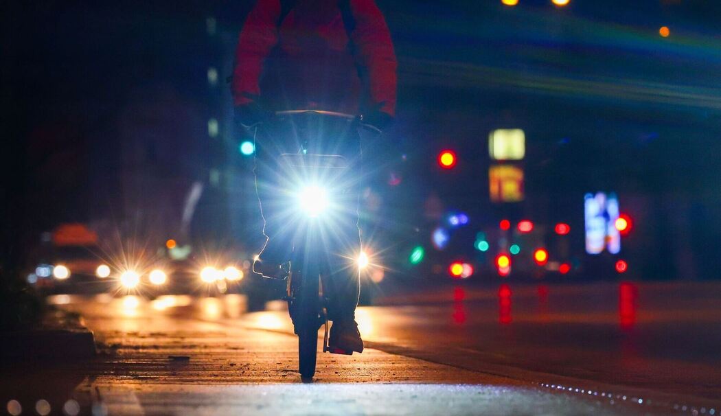 Radfahrer fährt mit Licht am Morgen eine Straße entlang Radfahrer fährt mit Licht am Morgen eine Straße entlang