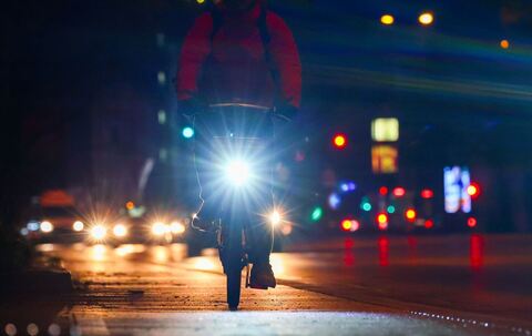 Radfahrer fährt mit Licht am Morgen eine Straße entlang