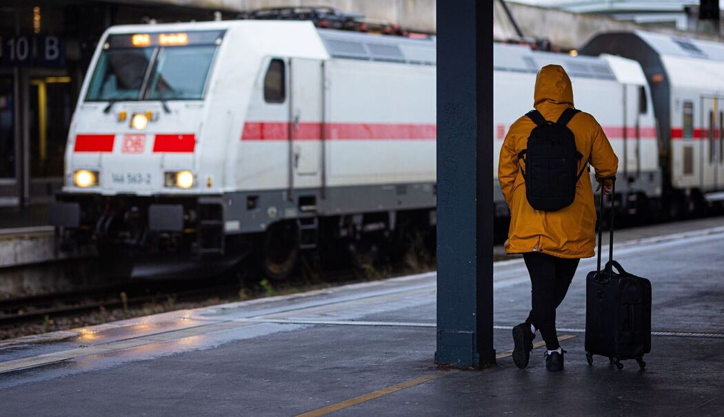 Reisende wartet bei Regen und Herbststurm am Bahnhof auf den Zug
