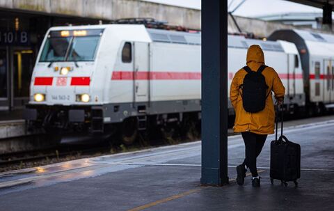 Reisende wartet bei Regen und Herbststurm am Bahnhof auf den Zug