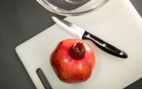 Granatapfel liegt neben einem Messer auf einem Tisch