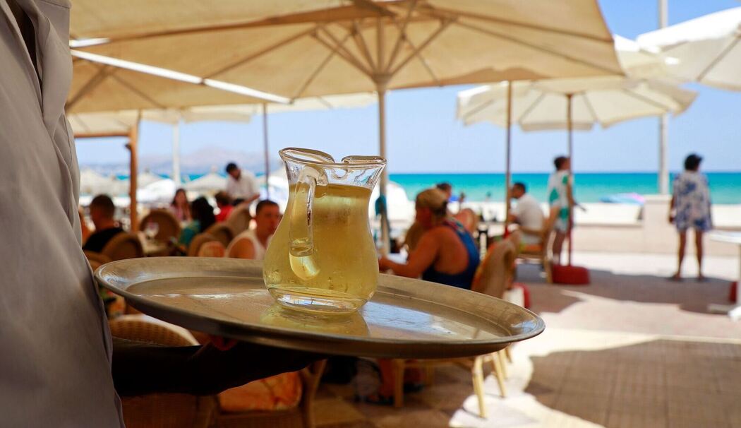 Kellner serviert am Strand einen Wein