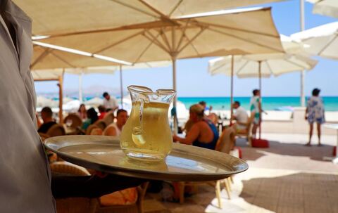 Kellner serviert am Strand einen Wein