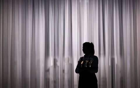 Eine Servicemitarbeiterin steht vor einem hellen Vorhang