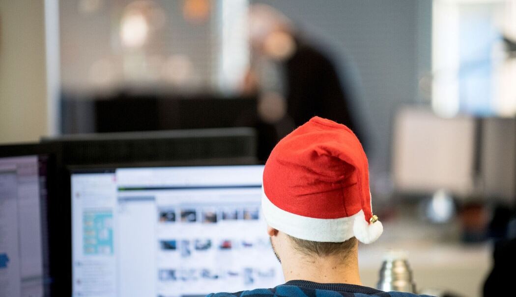 Ein Mann sitzt mit Weihnachtsmütze im Büro
