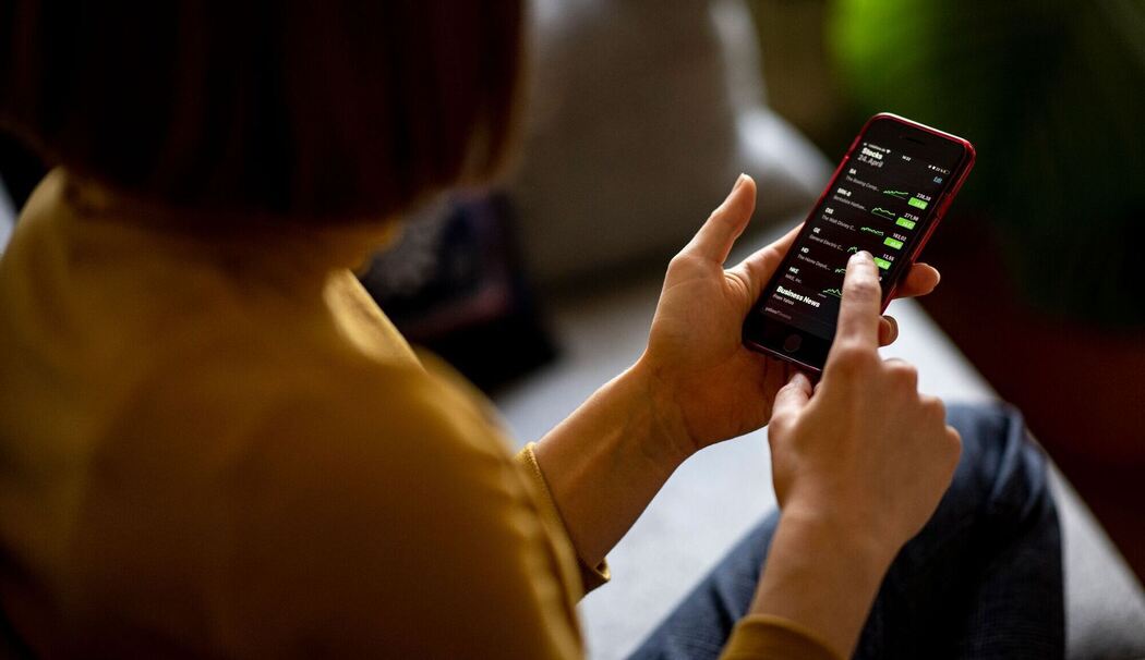 Eine Frau schaut auf ihrem Handy nach Aktien Eine Frau schaut auf ihrem Handy nach Aktien