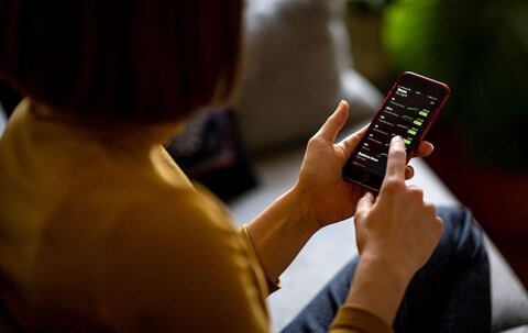 Eine Frau schaut auf ihrem Handy nach Aktien