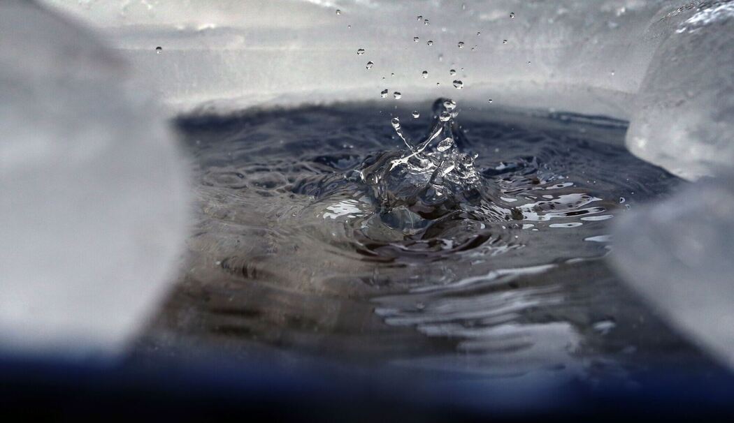 Wasser tropft in eine von Eis umgebene Regentonne Wasser tropft in eine von Eis umgebene Regentonne