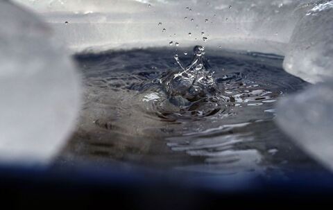 Wasser tropft in eine von Eis umgebene Regentonne