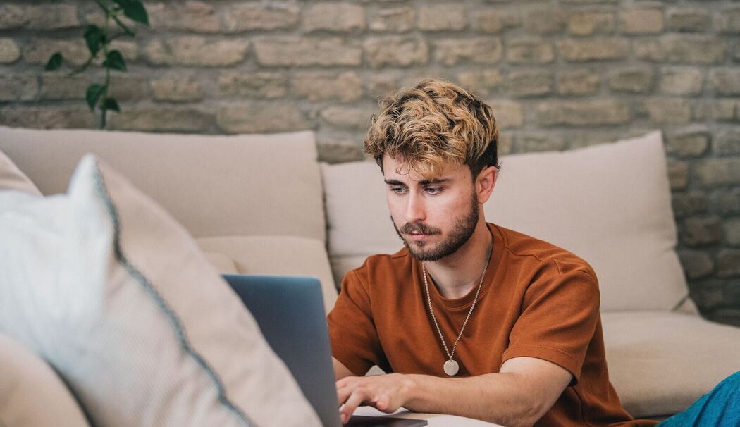 Ein Mann am Laptop auf einer Couch Ein Mann am Laptop auf einer Couch