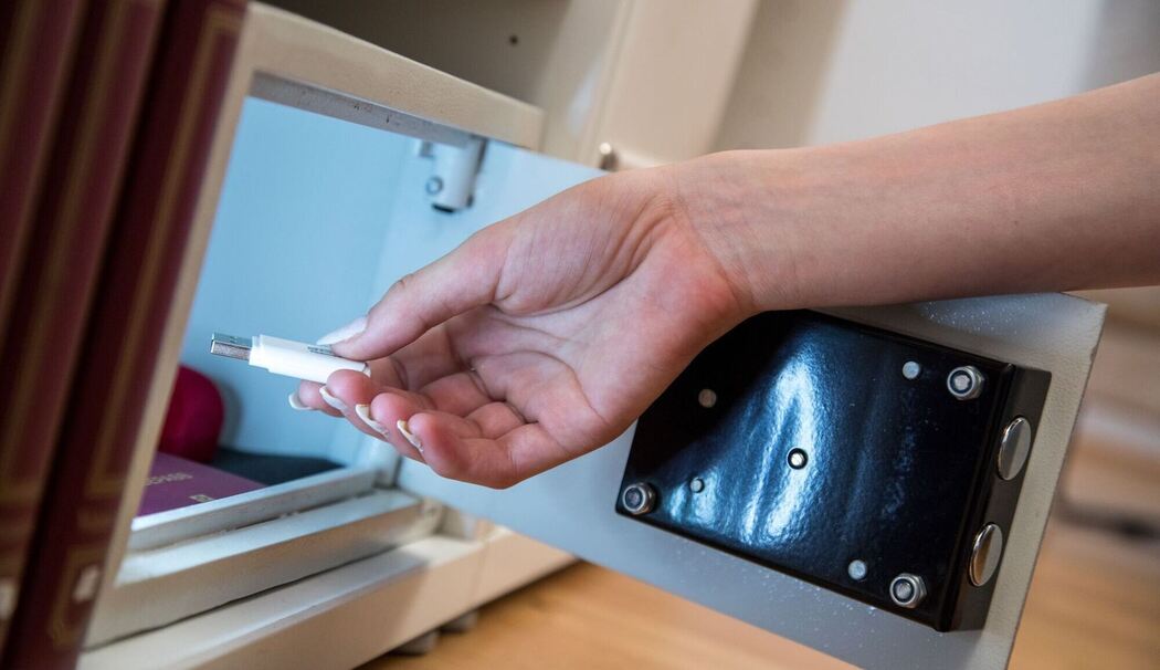 Eine Frau legt einen USB-Stick in einen Safe Eine Frau legt einen USB-Stick in einen Safe
