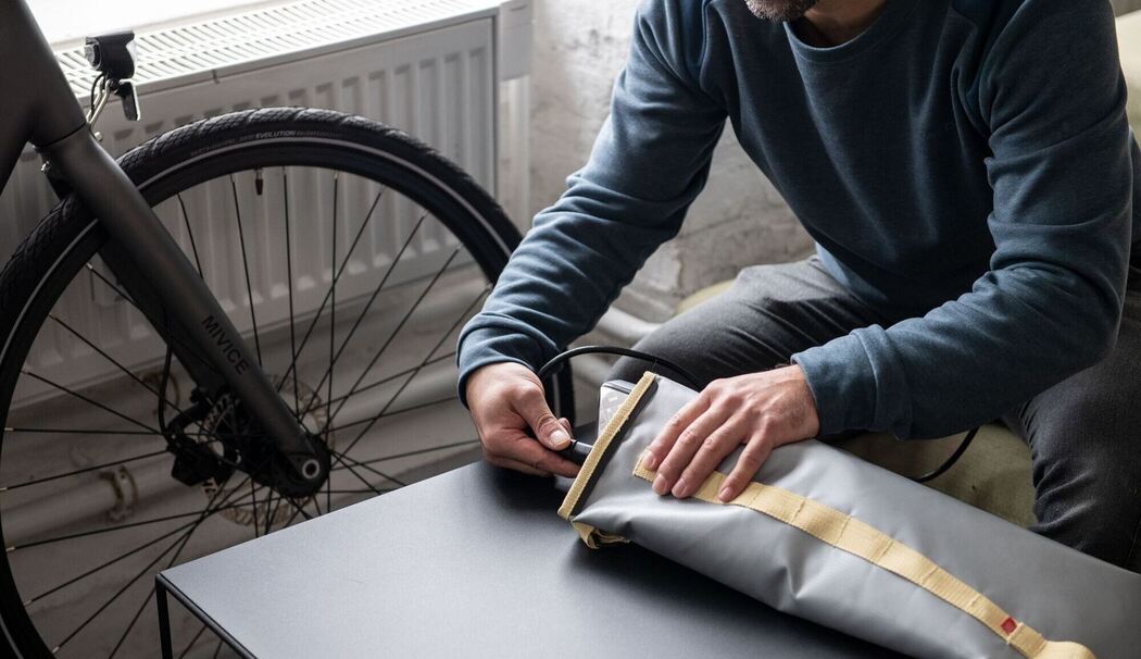 Ein Mann lädt einen E-Bike-Akku in einer feuerfesten Akku-Tasche