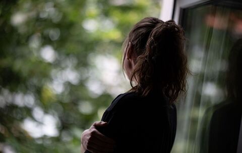 Eine Frau schaut nachdenklich aus dem Fenster