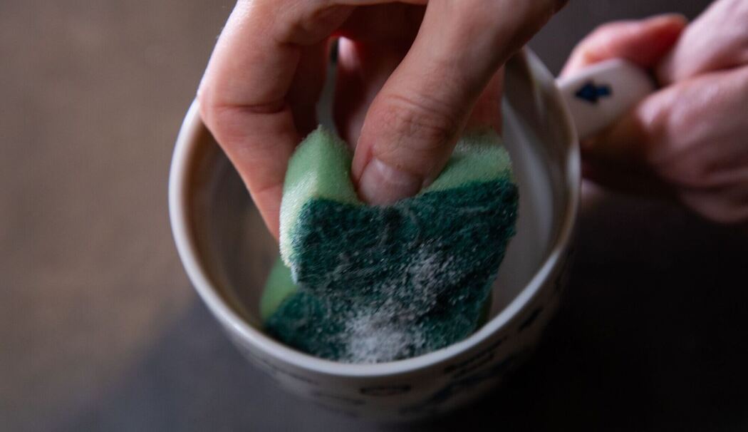 Tasse wird mit einem Schwamm gereinigt