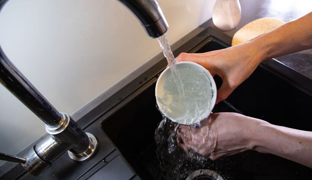 Tasse wird mit klarem Wasser ausgespült