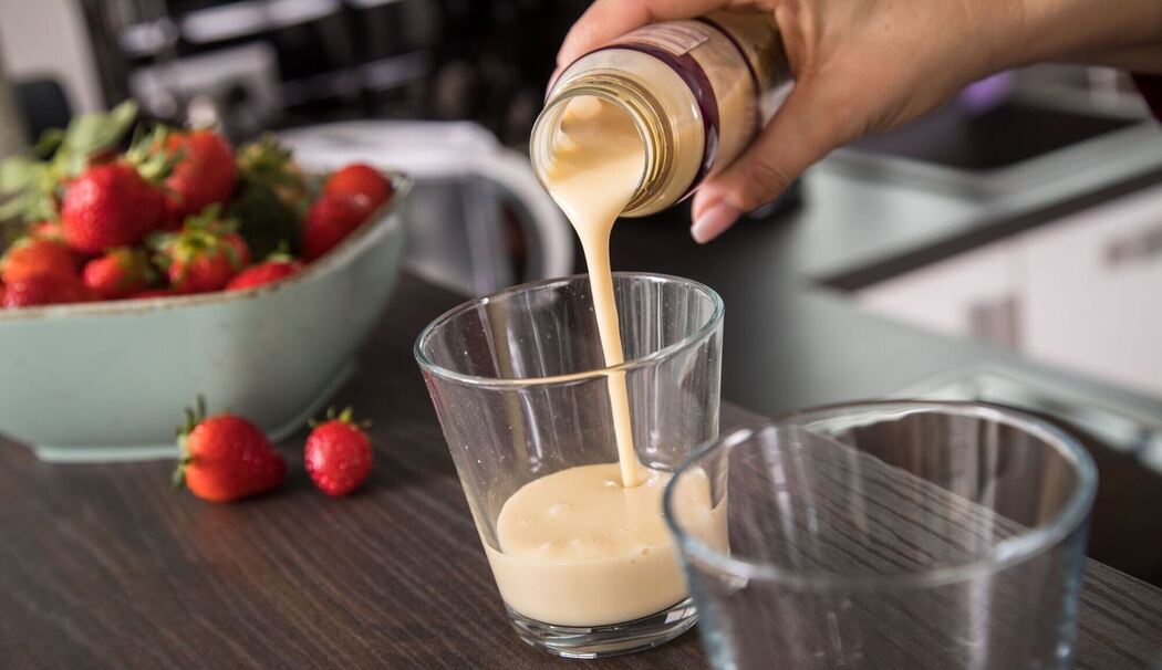 Eine Frau gießt ein Fertig-Getränk in ein Glas