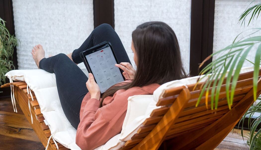 Eine Frau guckt auf einem Tablet auf einen Kalender