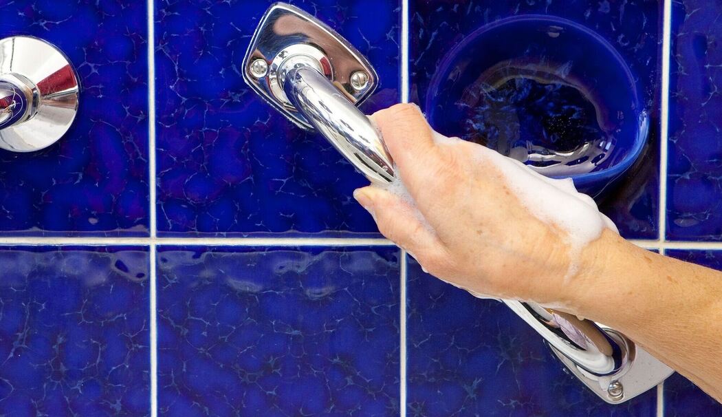 Eine Hand greift einen Haltegriff im Bad