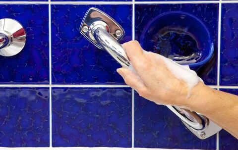 Eine Hand greift einen Haltegriff im Bad