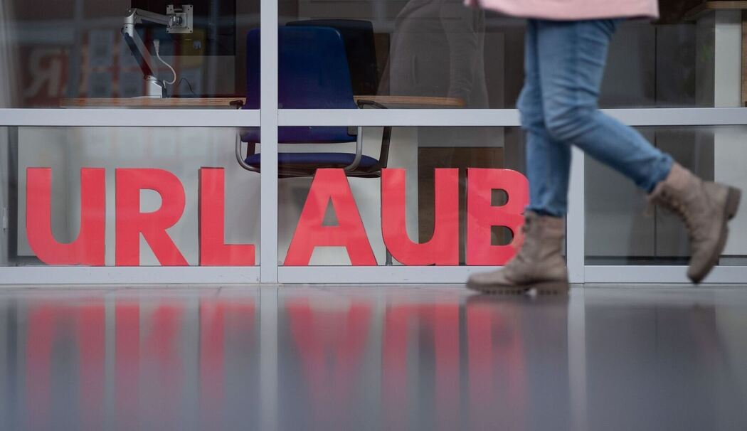 Eine Frau läuft an den Buchstaben Urlaub vorbei
