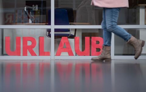 Eine Frau läuft an den Buchstaben Urlaub vorbei