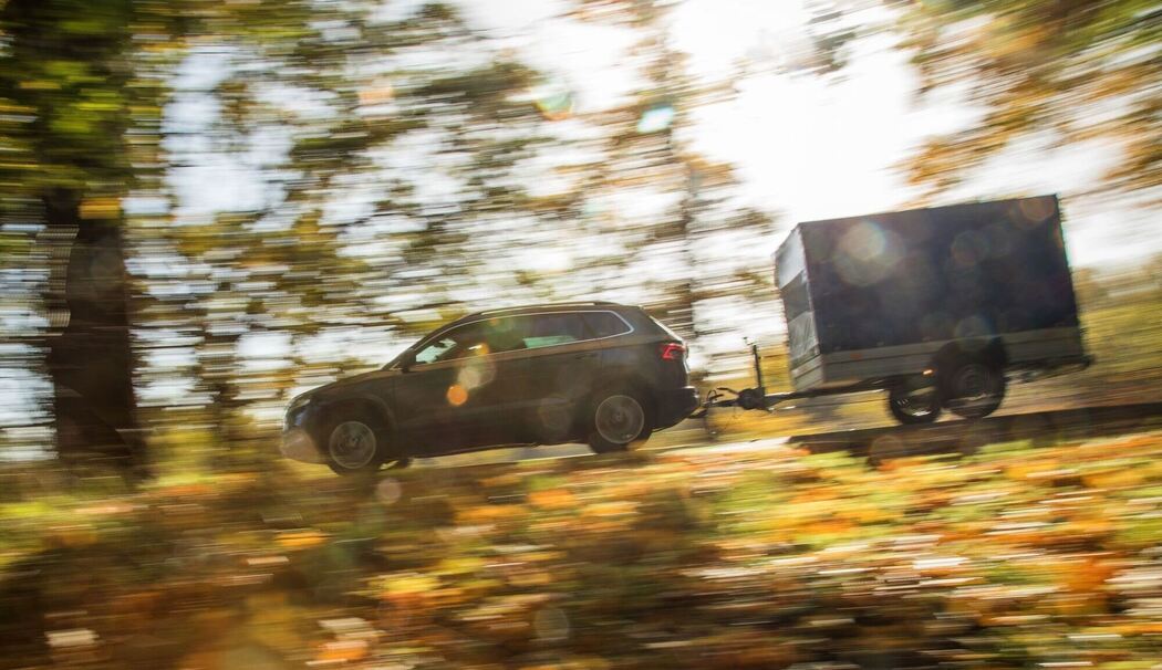 Ein Auto mit Anhänger fährt die Straße entlang