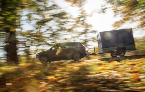 Ein Auto mit Anhänger fährt die Straße entlang