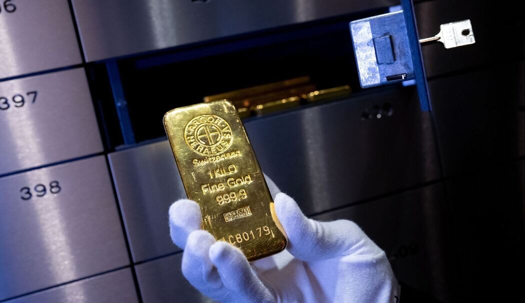 Ein Mann legt einen Goldbarren in ein Schließfach