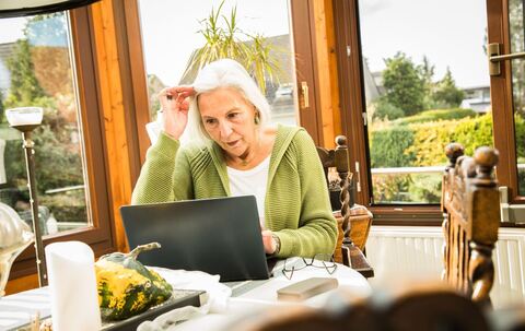 Eine Seniorin arbeitet an ihrem Laptop