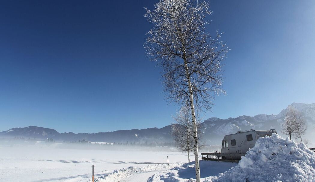 Wintercamper mit Wohnmobil auf einem Campingplatz