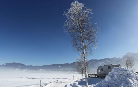Wintercamper mit Wohnmobil auf einem Campingplatz