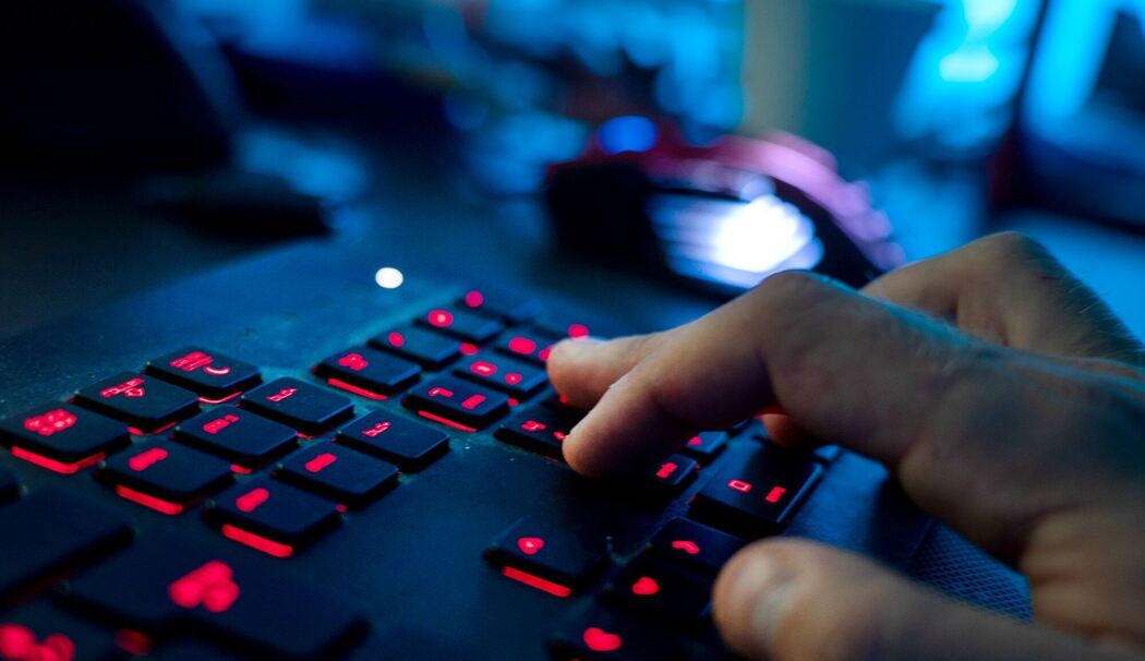 Ein Mann sitzt am Rechner und tippt auf einer Tastatur