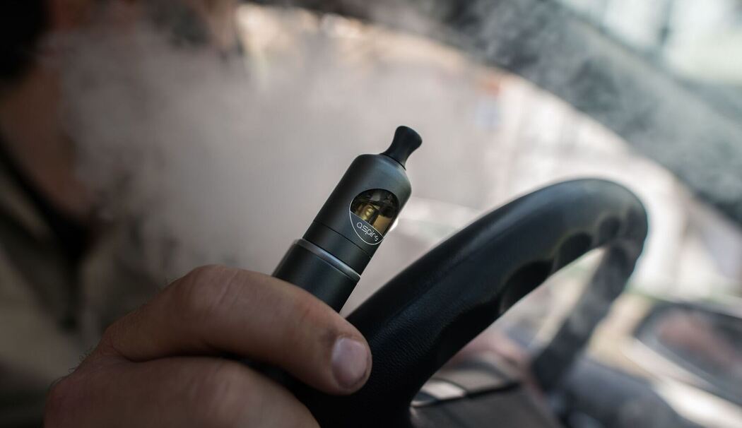 Ein Mann raucht eine E-Zigarette im Auto Ein Mann raucht eine E-Zigarette im Auto