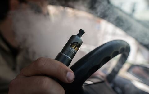 Ein Mann raucht eine E-Zigarette im Auto