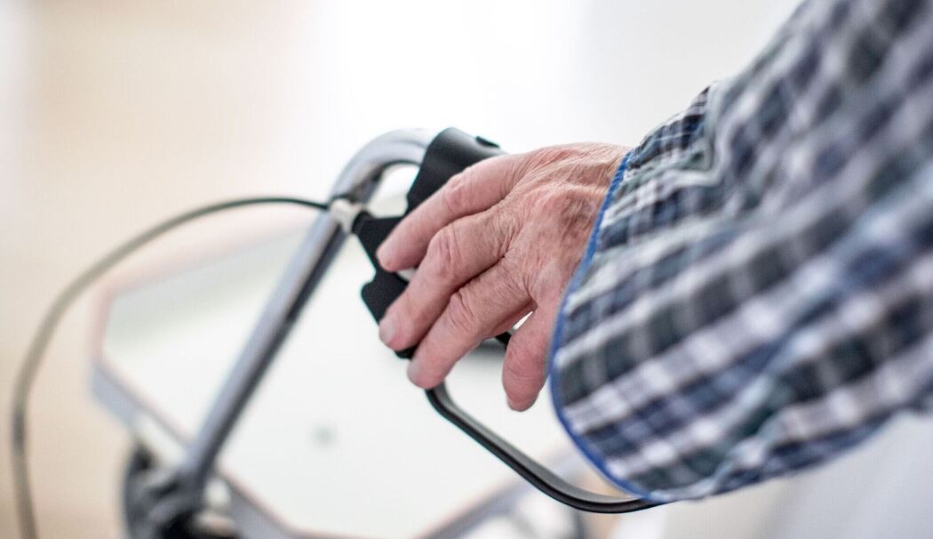 Mann stützt sich auf seinen Rollator