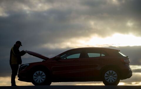 Mann öffnet die Motohaube eines Autos