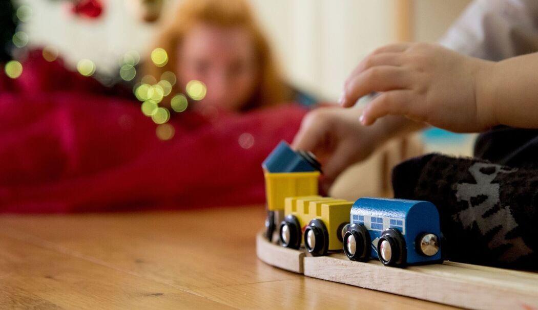 Ein Kind spielt mit einer Holzeisenbahn