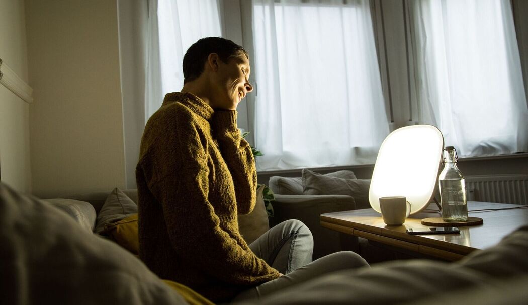 Frau sitzt vor einer Tageslichtlampe
