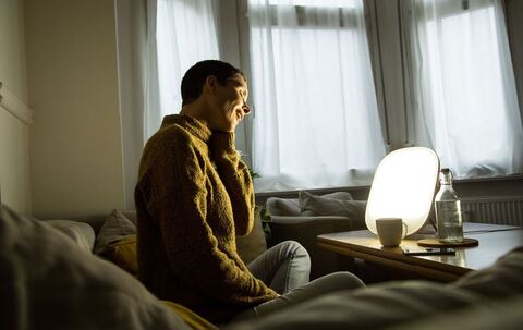 Frau sitzt vor einer Tageslichtlampe