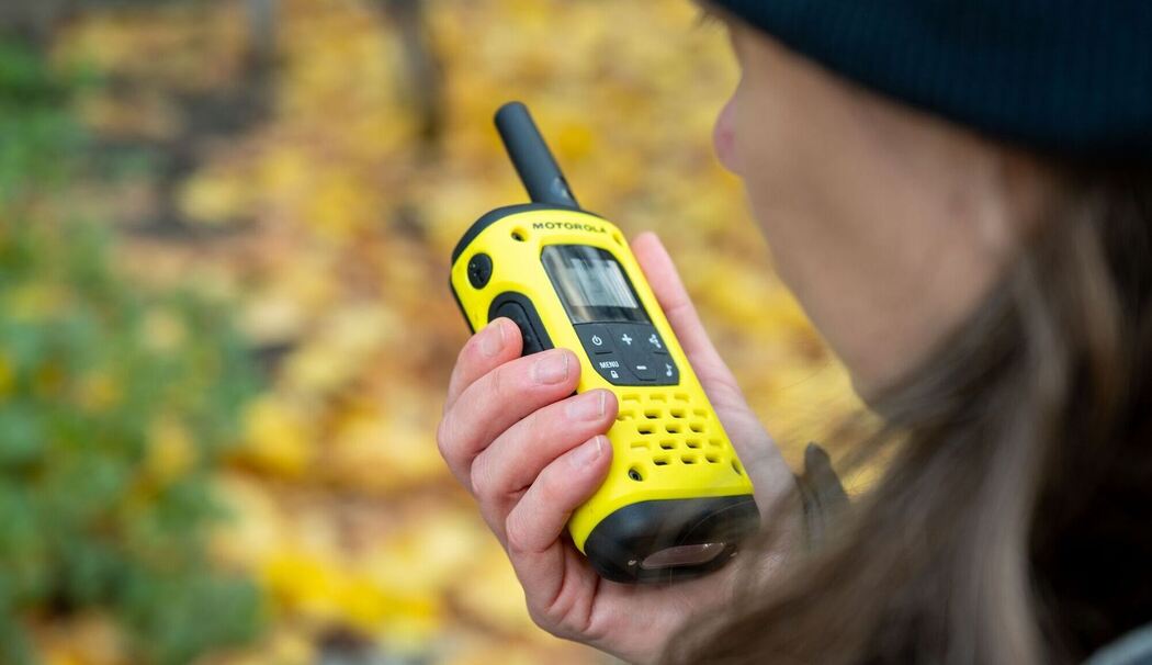 Eine Frau spricht in ein Walkie-Talkie in ihrer Hand