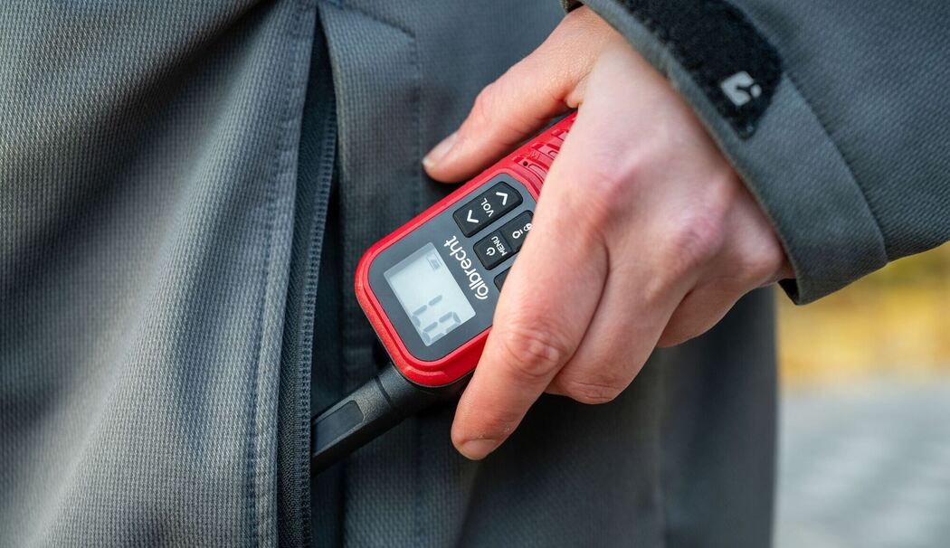 Eine Frau holt ein Walkie-Talkie aus ihrer Jackentasche