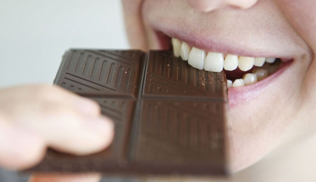 Frau beißt in ein Stück Schokolade