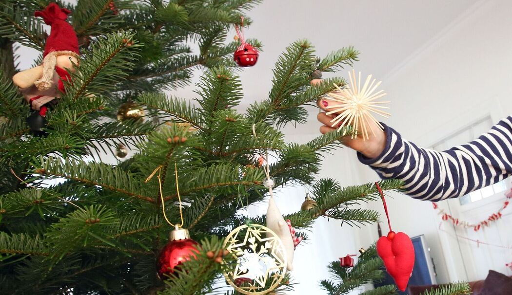 Mädchen schmückt einen Weihnachtsbaum